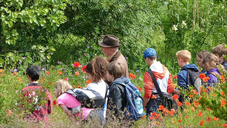 Ein Mann leitet eine Gruppe von Kindern durch die Natur.