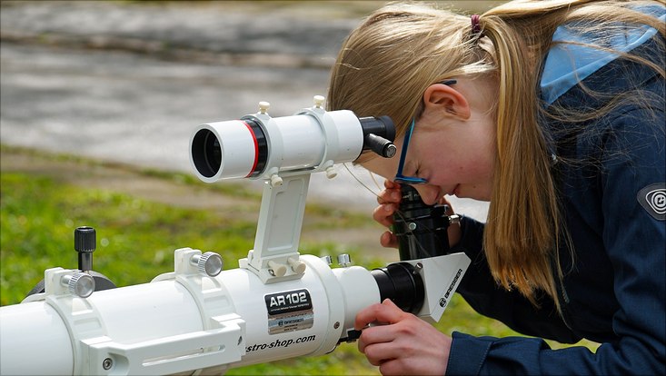 Eine junge Frau schaut durch ein Teleskop