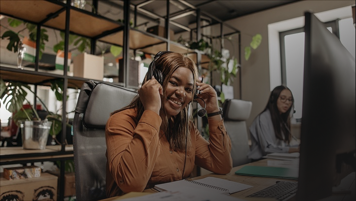 Frau mit Headset vor Monitor