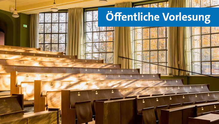 Hörsaal in den durch eine Fensterfront die Sonne scheint. Die Bänke mit Klappstühlen und Klapptischen sind hintereinander aufgereiht und aus hellem Holz